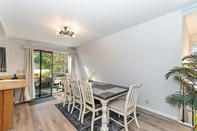 dining area with a notable chandelier, baseboards, and light wood-type flooring