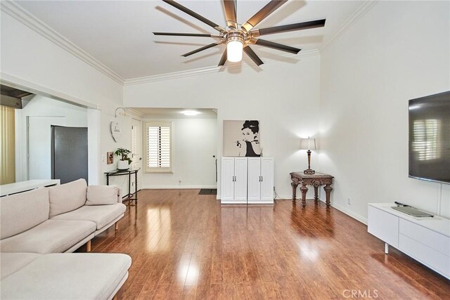 living room featuring baseboards, wood finished floors, ornamental molding, and a ceiling fan