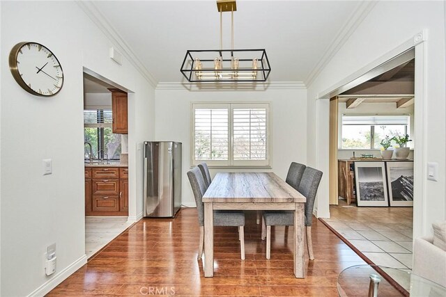 dining area with wood finished floors, crown molding, a chandelier, and beverage cooler