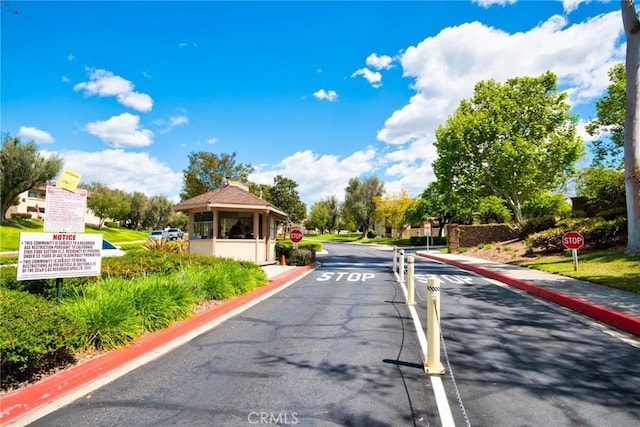 view of street featuring sidewalks, a gated entry, curbs, and traffic signs
