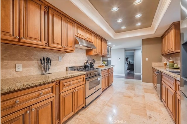2333 N Coronet Ct, Covina, CA 91724 - kitchen with under cabinet range hood, appliances with stainless steel finishes, brown cabinets, baseboards, and a tray ceiling