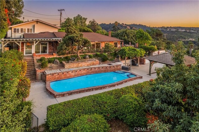 2333 N Coronet Ct, Covina, CA 91724 - pool at dusk featuring an outdoor pool, a pergola, and a patio area
