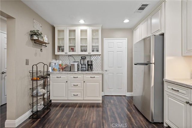 kitchen featuring dark wood finished floors, visible vents, freestanding refrigerator, baseboards, and white cabinetry