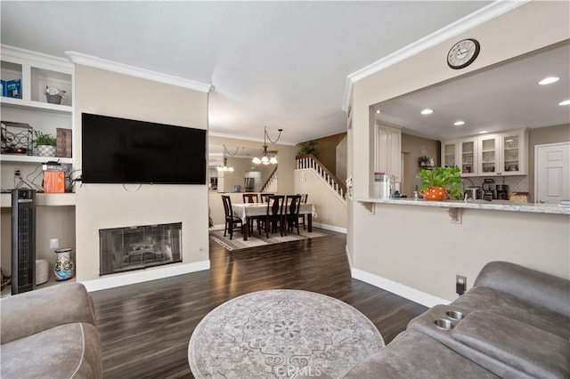 living room featuring dark wood-type flooring, a chandelier, crown molding, and recessed lighting
