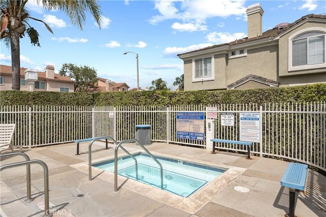 view of swimming pool featuring a community hot tub and fence
