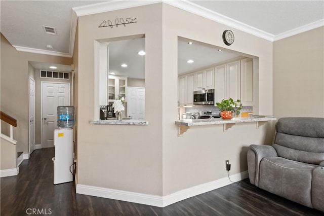 interior space with stainless steel microwave, ornamental molding, dark wood-style floors, and visible vents