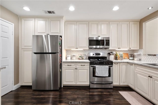 kitchen featuring backsplash, visible vents, dark wood-style floors, and stainless steel appliances