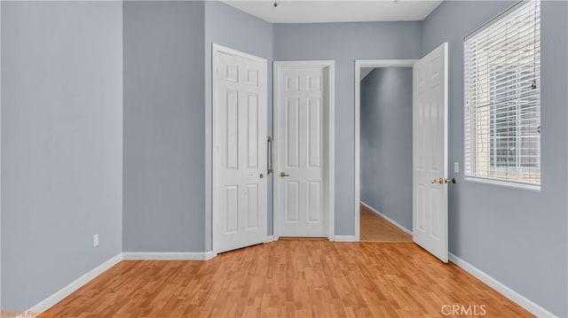 unfurnished bedroom featuring a closet, baseboards, and light wood finished floors