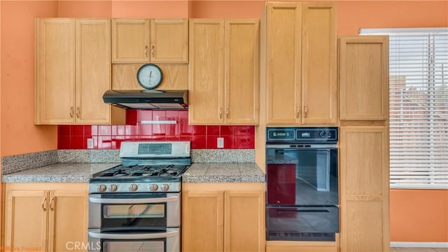 kitchen featuring a warming drawer, under cabinet range hood, black oven, light brown cabinets, and range with two ovens