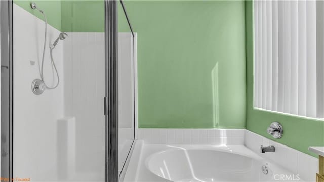 bathroom featuring a shower stall and a bath