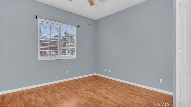 spare room featuring baseboards, a ceiling fan, and wood finished floors