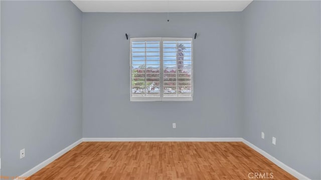 spare room featuring baseboards and wood finished floors