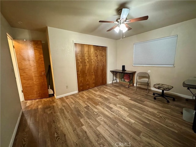 bedroom with baseboards, a ceiling fan, wood finished floors, and a closet