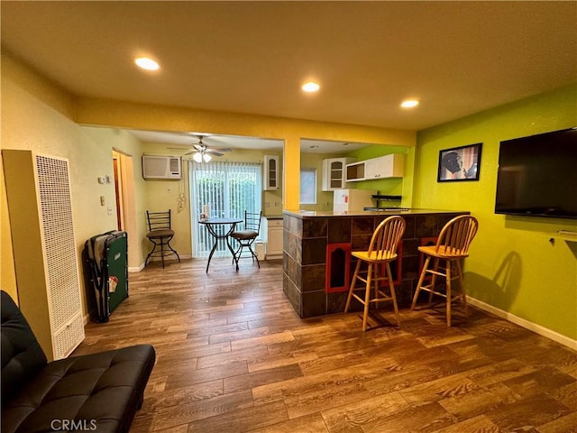 bar with a wall mounted air conditioner, a ceiling fan, a dry bar, dark wood-type flooring, and baseboards