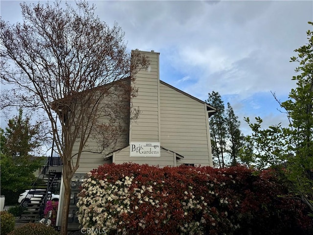 view of property exterior with a chimney and stairs
