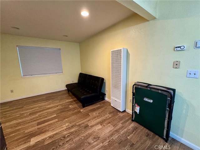 living area featuring baseboards, wood finished floors, and a heating unit