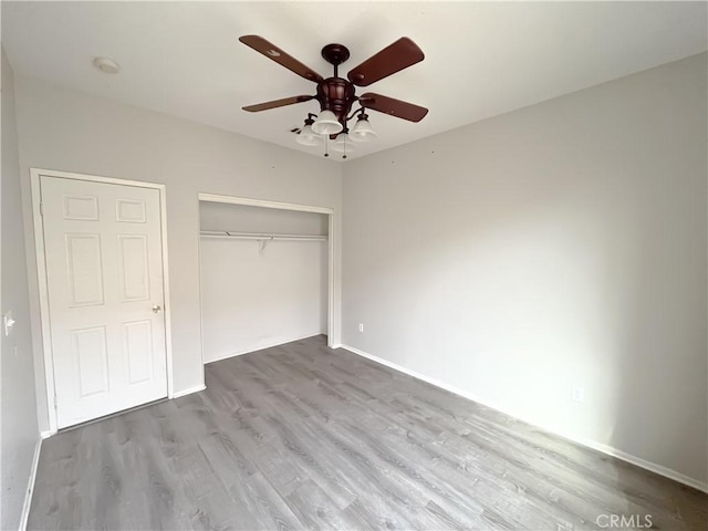 unfurnished bedroom featuring wood finished floors, a closet, and baseboards