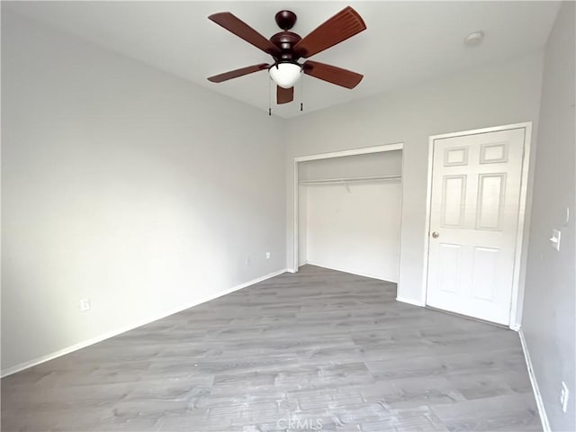 unfurnished bedroom with ceiling fan, baseboards, wood finished floors, and a closet