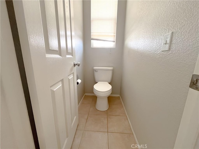 bathroom with baseboards, tile patterned flooring, and toilet