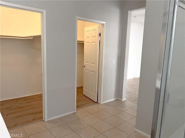 unfurnished bedroom with a walk in closet, baseboards, and light tile patterned flooring