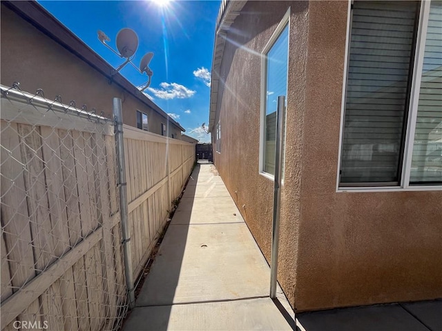 view of side of home with stucco siding and fence