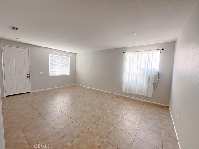 empty room featuring visible vents, baseboards, and light tile patterned floors