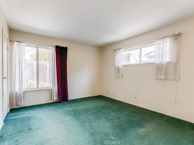 unfurnished room with carpet, baseboards, a textured ceiling, and a wealth of natural light