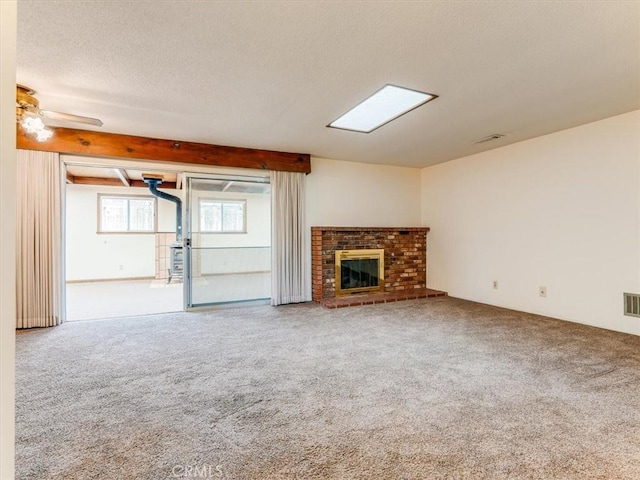 unfurnished living room with a brick fireplace, visible vents, carpet, and a textured ceiling