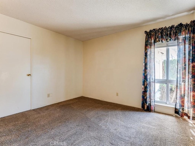 unfurnished room featuring carpet and a textured ceiling
