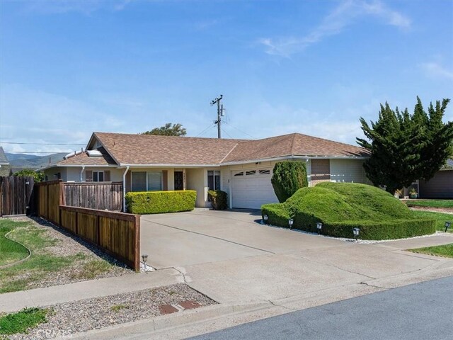 ranch-style home featuring driveway, an attached garage, and fence