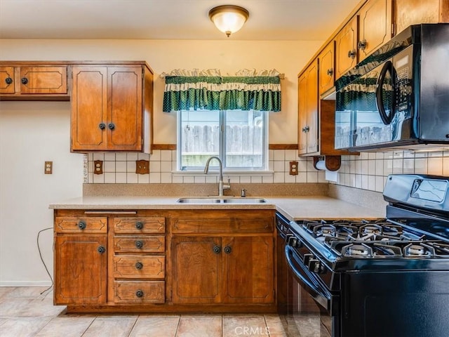 kitchen featuring a sink, brown cabinetry, black appliances, and decorative backsplash
