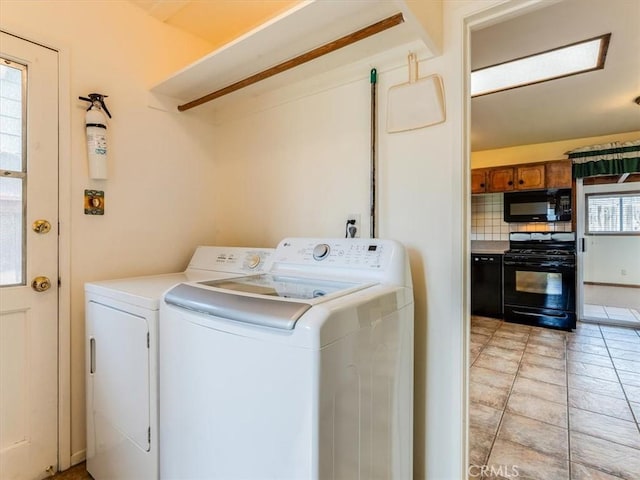 washroom featuring light tile patterned flooring, washing machine and dryer, and laundry area
