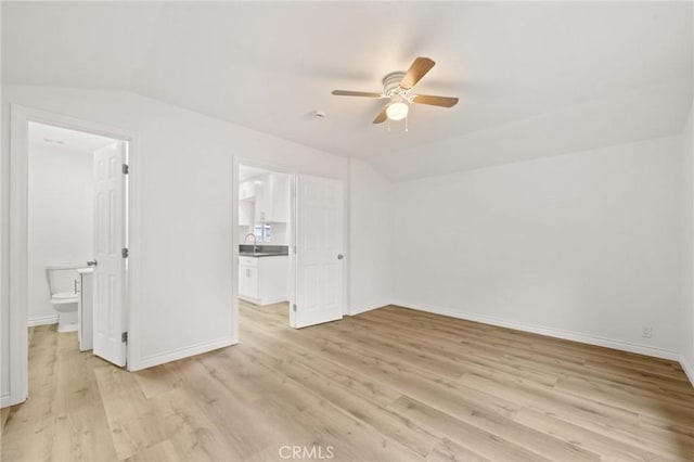 unfurnished bedroom with light wood-type flooring, baseboards, lofted ceiling, a ceiling fan, and connected bathroom