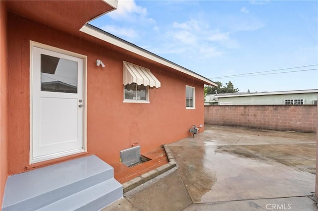 exterior space with fence, stucco siding, and a patio