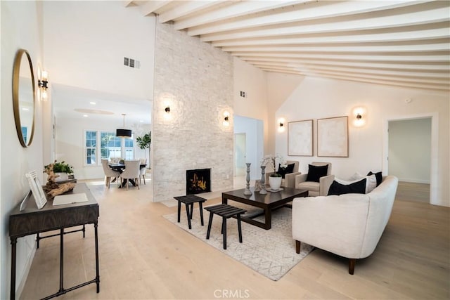 living room with high vaulted ceiling, beamed ceiling, visible vents, a fireplace, and wood finished floors