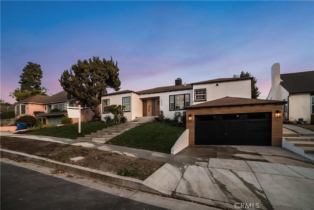 ranch-style house featuring a front lawn, driveway, and stucco siding
