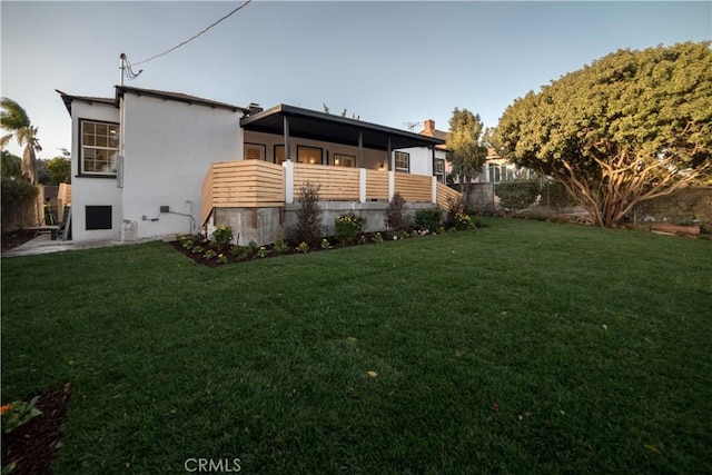 rear view of property featuring a lawn and stucco siding
