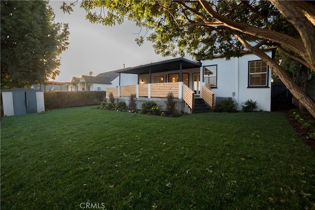back of house with a sunroom, fence, a storage shed, an outbuilding, and a yard