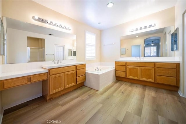 391 Camino Carta, San Marcos, CA 92078 - bathroom featuring a garden tub, two vanities, wood finished floors, a sink, and a stall shower