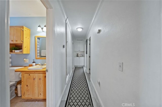 hall with a sink, light tile patterned floors, and crown molding