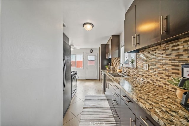 kitchen with backsplash, ceiling fan, a sink, appliances with stainless steel finishes, and light tile patterned floors