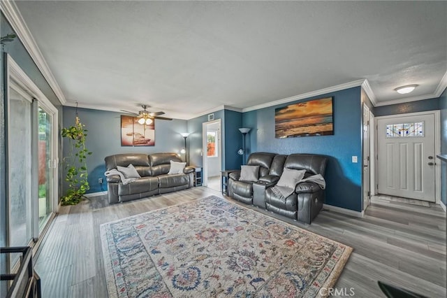 living area with baseboards, a ceiling fan, wood finished floors, and ornamental molding