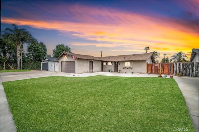 view of front of house featuring a front lawn, fence, stucco siding, concrete driveway, and an attached garage