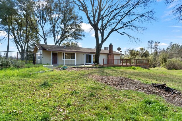 rear view of property with a yard, a chimney, fence, and a deck
