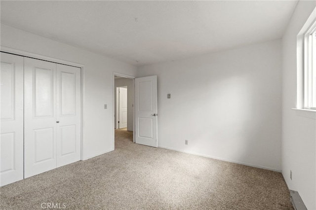 unfurnished bedroom featuring baseboards, carpet flooring, multiple windows, and a closet