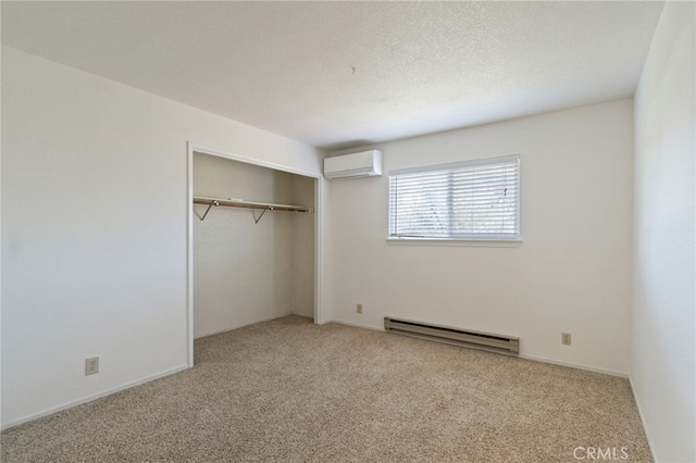 unfurnished bedroom with carpet floors, a closet, a baseboard radiator, and a wall mounted air conditioner
