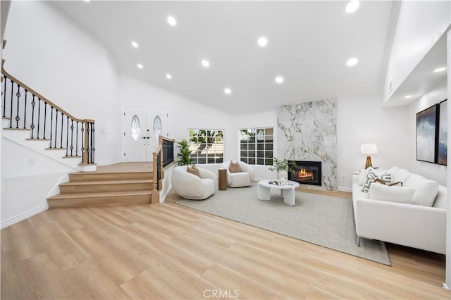 living room featuring wood finished floors, high vaulted ceiling, stairway, recessed lighting, and a high end fireplace