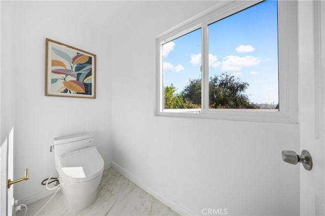 bathroom featuring baseboards, marble finish floor, and toilet