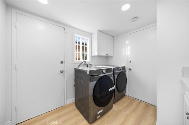 laundry room featuring cabinet space, light wood-style floors, and washer and dryer