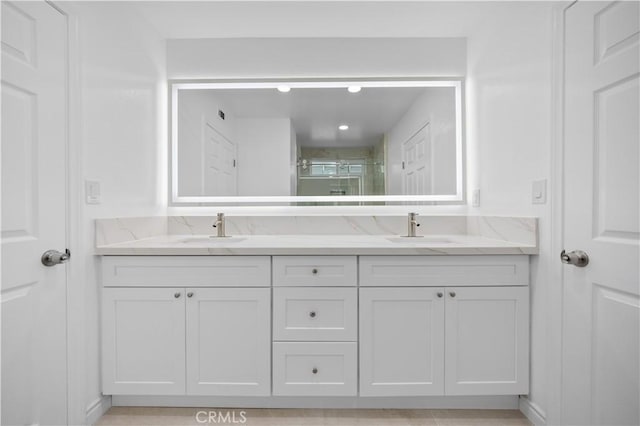 bathroom featuring double vanity, a shower stall, and a sink